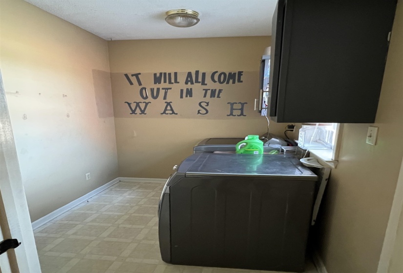 Washroom featuring light flooring, washing machine and dryer, and cabinet space