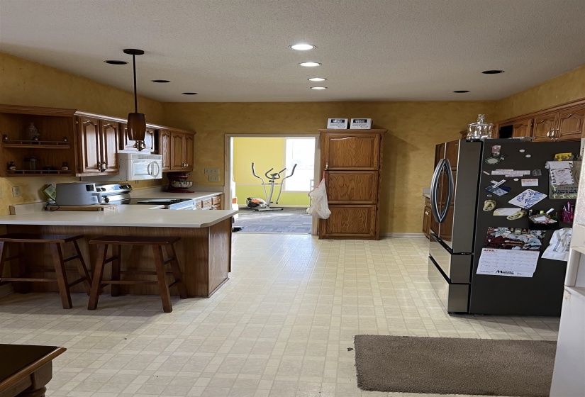 Kitchen with light flooring, light countertops, stainless steel appliances, a kitchen bar, and open shelves