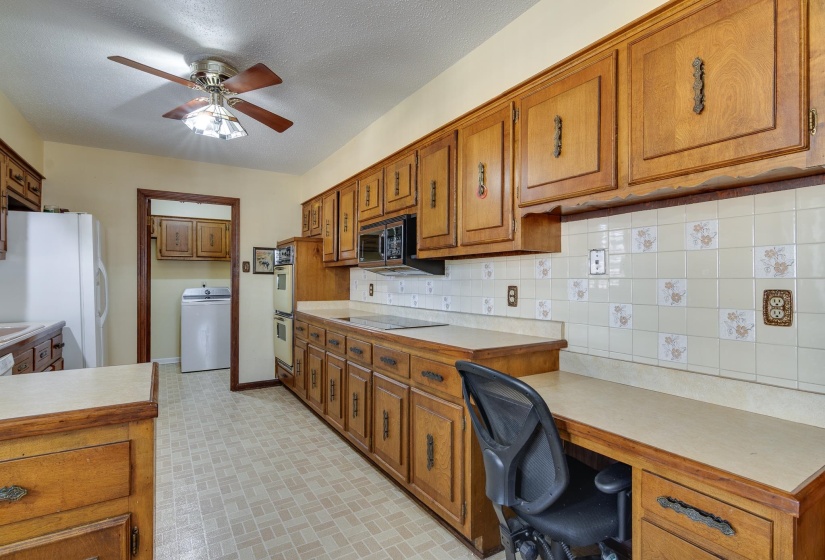 Kitchen with light countertops, brown cabinets, washer / dryer, tasteful backsplash, and white appliances