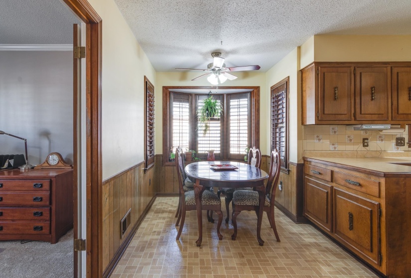 Dining space with a textured ceiling, wainscoting, a ceiling fan, and wood walls