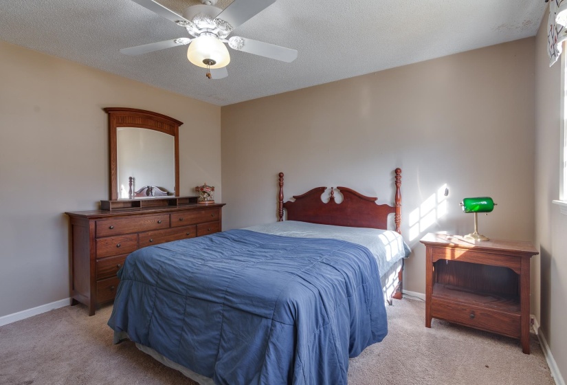 Carpeted bedroom with a ceiling fan and a textured ceiling