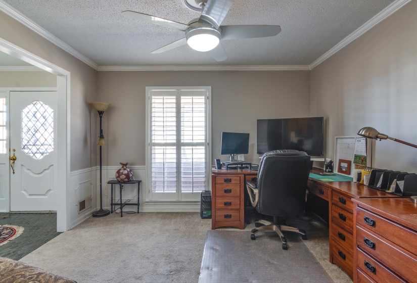 Office space featuring a wainscoted wall, light carpet, crown molding, a ceiling fan, and a decorative wall