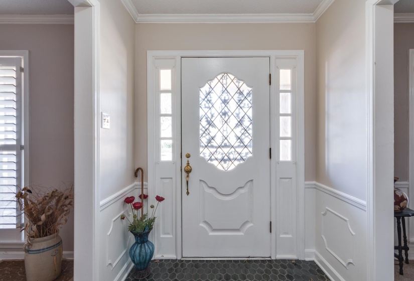 Entryway with ornamental molding, healthy amount of natural light, and a wainscoted wall