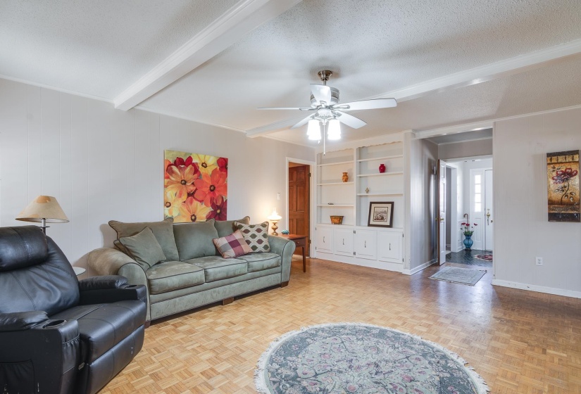 Living area featuring beam ceiling, a textured ceiling, and ceiling fan