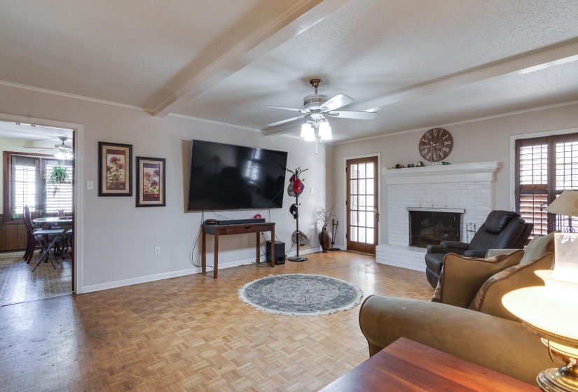 Living area with a ceiling fan, beamed ceiling, a textured ceiling, and a fireplace