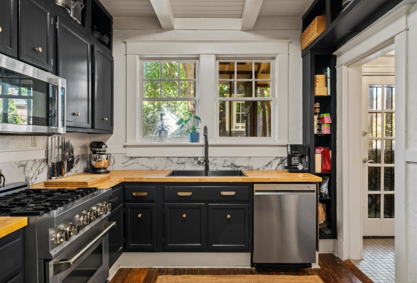 Kitchen with dark cabinets, stainless steel appliances, wooden counters, dark wood-style floors, and a wooden ceiling with exposed beams