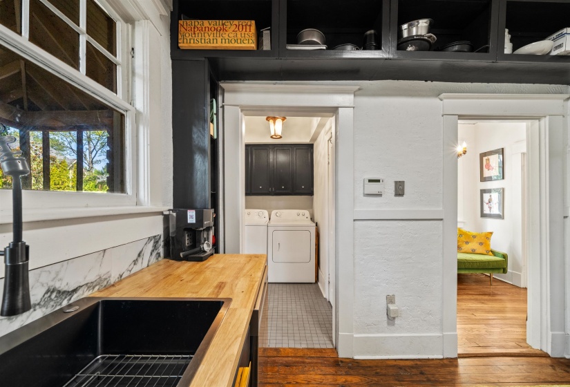 Kitchen featuring dark cabinets, butcher block countertops, washer and dryer, and dark wood finished floors