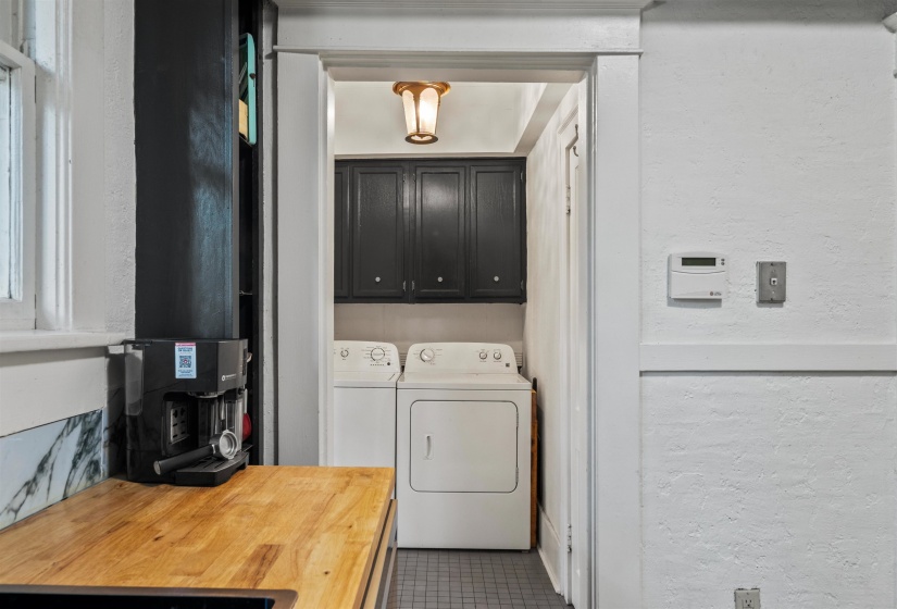 Laundry room with a textured wall, independent washer and dryer, cabinet space, and dark tile patterned flooring