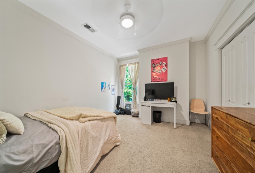 Bedroom with ornamental molding, light colored carpet, and ceiling fan