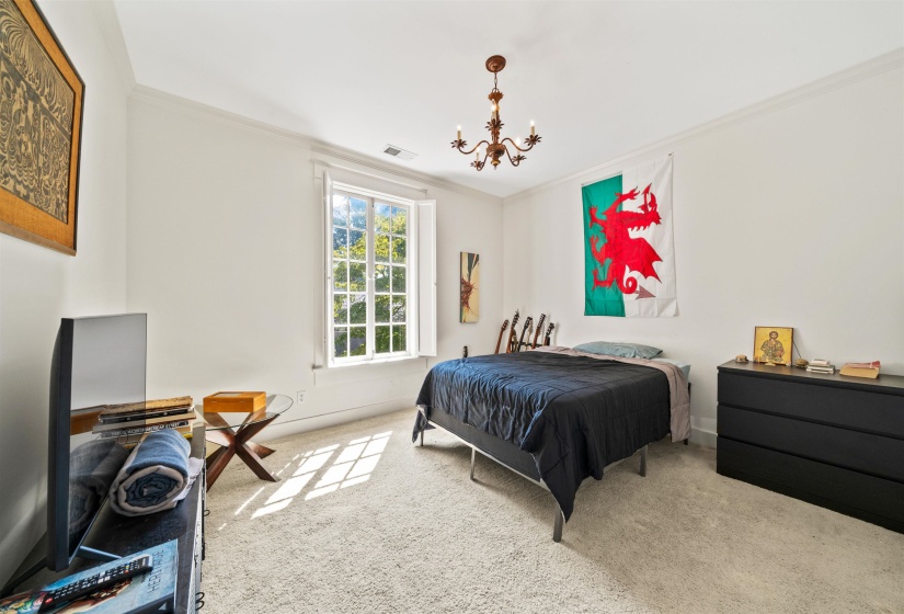 Carpeted bedroom with ornamental molding and a chandelier