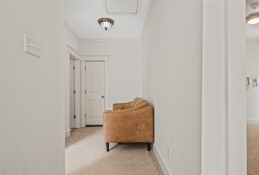 Corridor with light colored carpet and ornamental molding