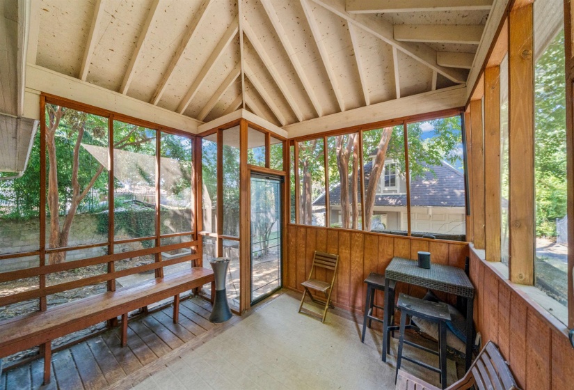 Sunroom featuring lofted ceiling, healthy amount of natural light, tile patterned floors, and wooden walls