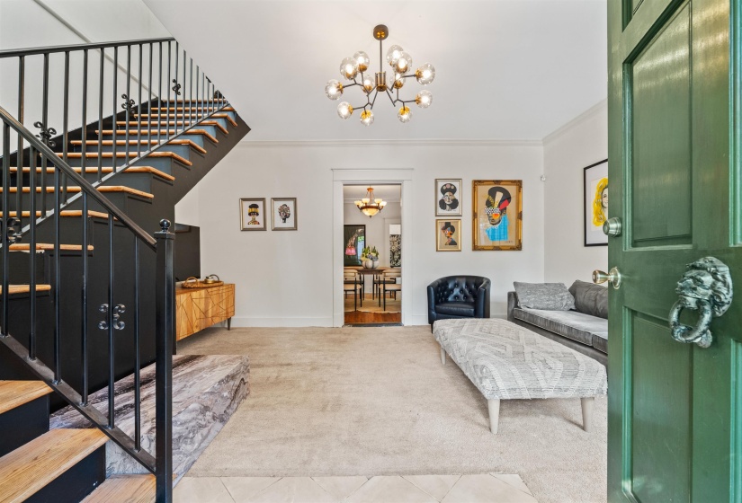 Living area featuring stairs, a chandelier, ornamental molding, and carpet flooring