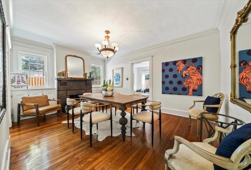 Dining area with hardwood / wood-style flooring, ornamental molding, a stone fireplace, and a chandelier