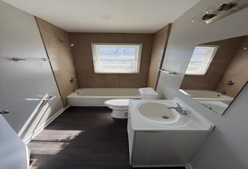 Bathroom with vanity, bathing tub / shower combination, and dark wood-style floors