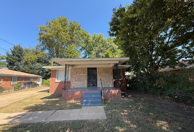 Bungalow-style house with a front lawn, covered porch, and stone siding