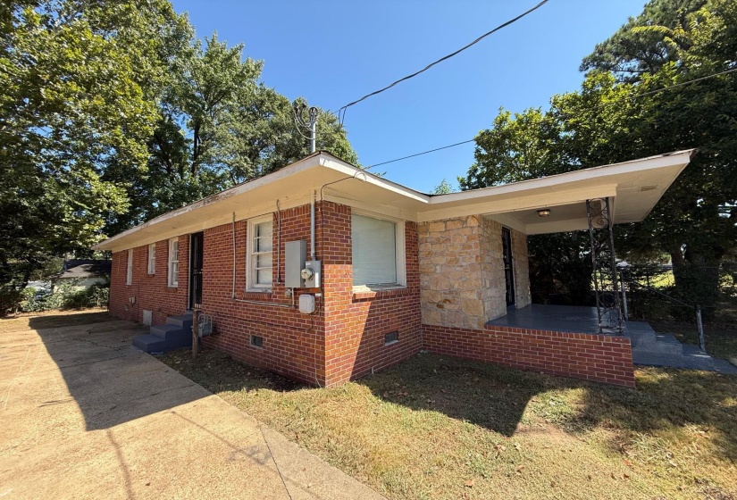 View of side of property featuring crawl space, brick siding, a yard, a patio, and stone siding
