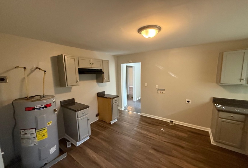 Kitchen with dark countertops, water heater, and dark wood finished floors