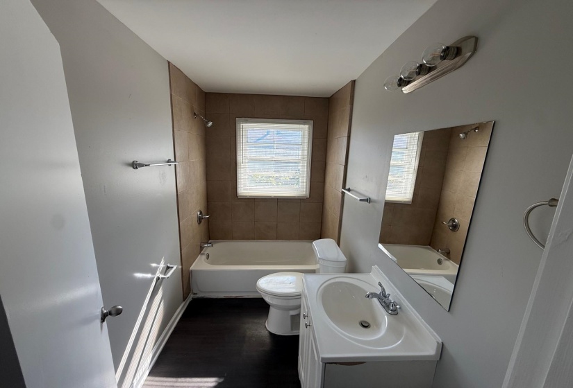 Bathroom featuring bathtub / shower combination, vanity, and dark wood-type flooring