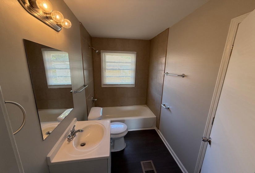 Full bath featuring vanity, bathing tub / shower combination, and dark wood-type flooring
