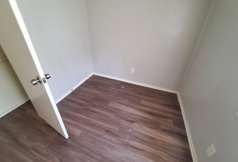 Empty room featuring dark wood-style flooring and baseboards