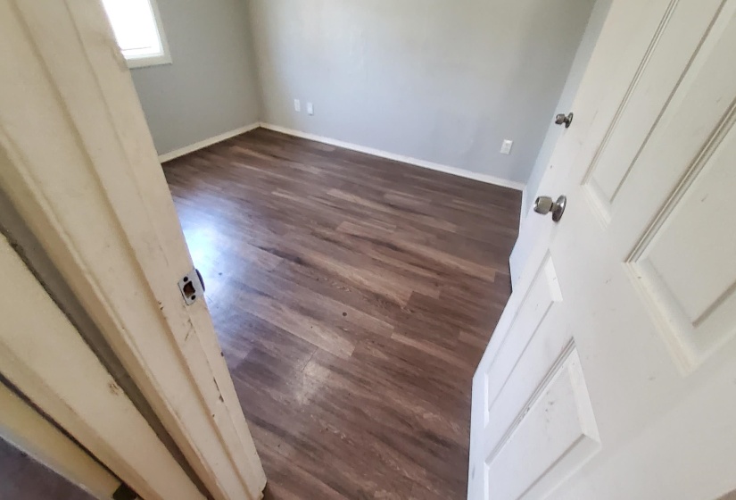 Unfurnished bedroom featuring dark wood-type flooring and baseboards