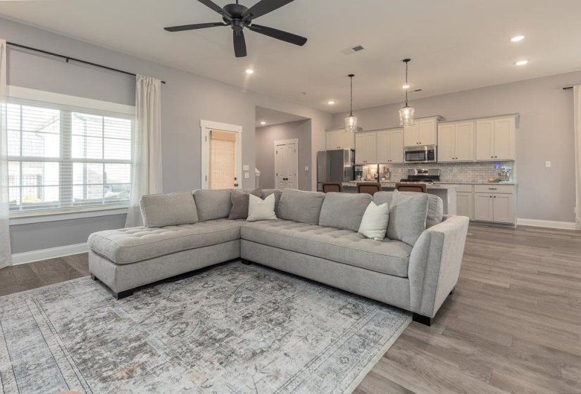 Living area featuring light wood-style flooring, a ceiling fan, and recessed lighting
