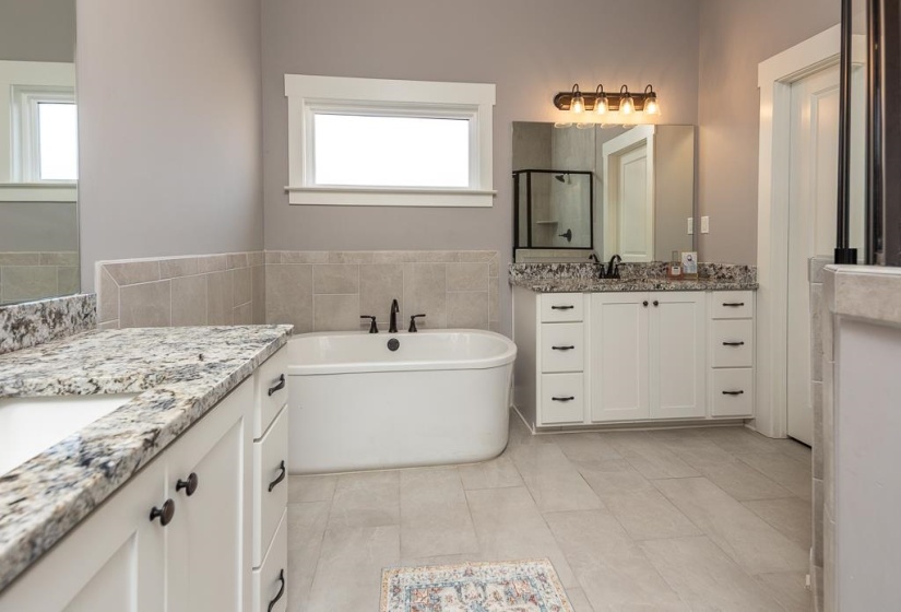 Bathroom featuring a freestanding tub, two vanities, a stall shower, and light tile patterned flooring