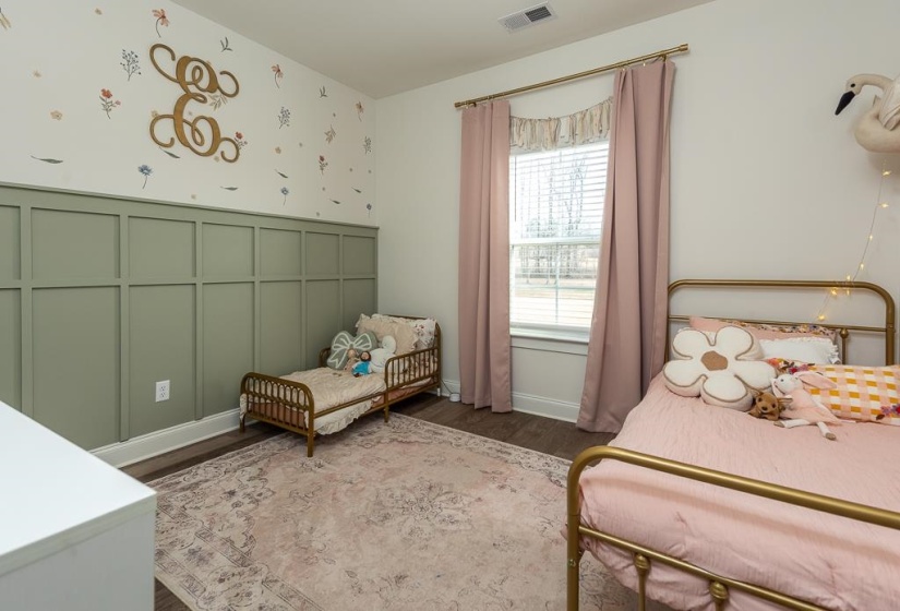 Bedroom with a decorative wall and dark wood-style floors