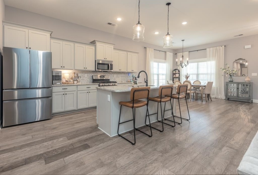 Kitchen with stainless steel appliances, hanging light fixtures, a chandelier, a breakfast bar, and tasteful backsplash