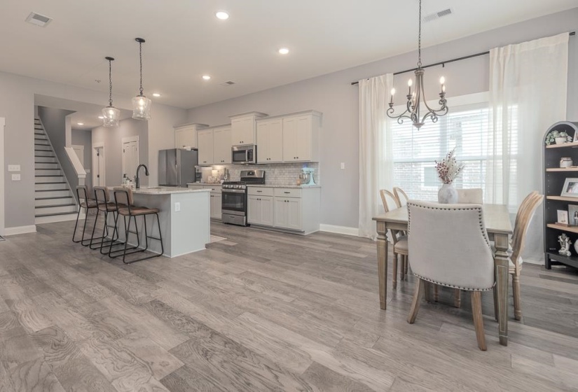 Kitchen with a chandelier, a kitchen bar, appliances with stainless steel finishes, white cabinetry, and an island with sink