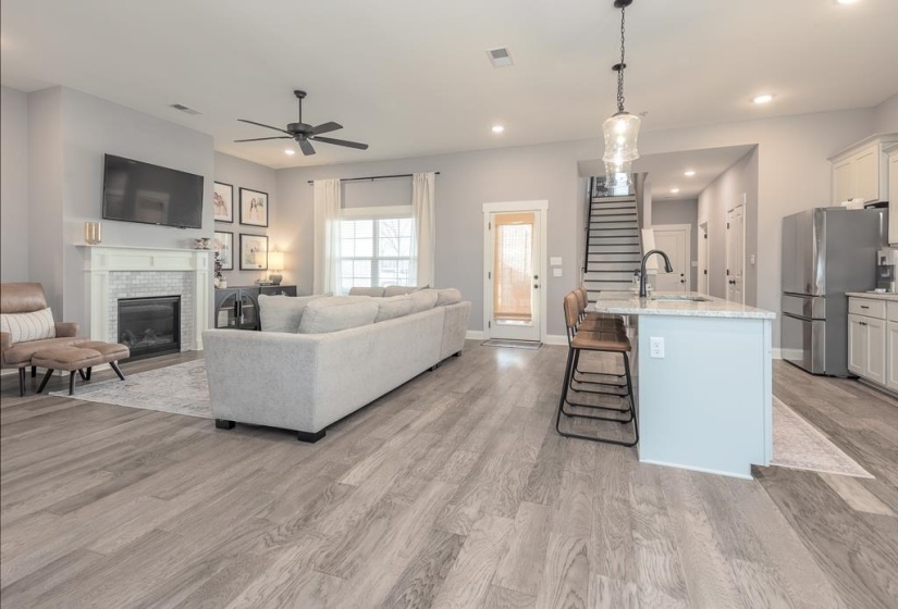 Living area featuring stairs, recessed lighting, light wood-style floors, a glass covered fireplace, and a ceiling fan