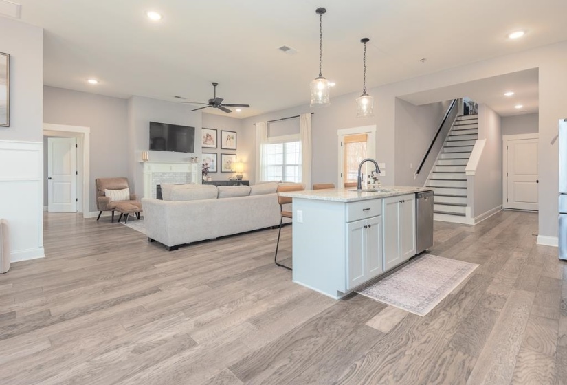 Kitchen featuring a kitchen island with sink, decorative light fixtures, a kitchen bar, light stone countertops, and white cabinetry