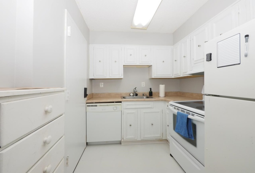 Kitchen featuring white appliances, light countertops, and white cabinetry