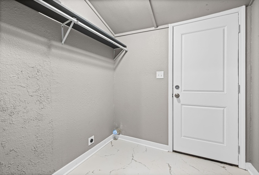 Laundry room featuring light marble finish floors, a textured wall, and electric dryer hookup