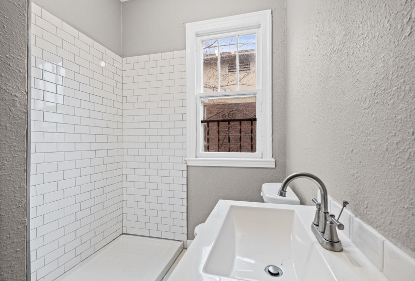 Full bathroom with a textured wall and a stall shower