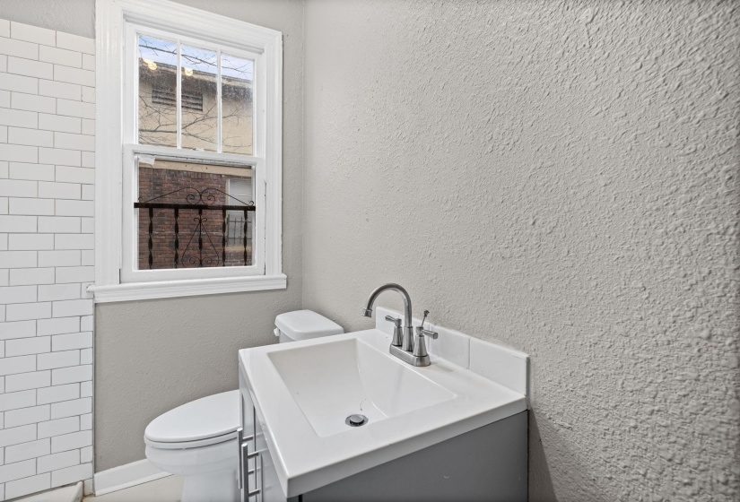 Full bathroom with a textured wall, vanity, and tiled shower