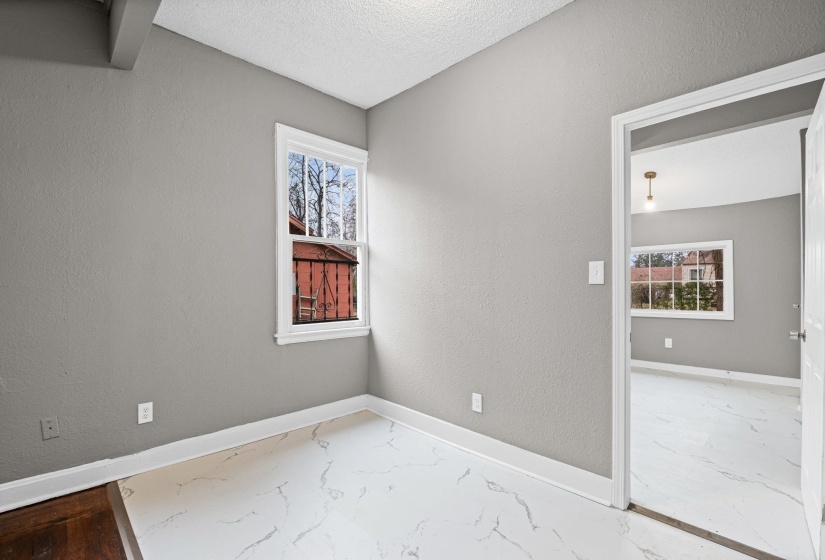 Empty room with marble finish flooring, a textured wall, plenty of natural light, and a textured ceiling