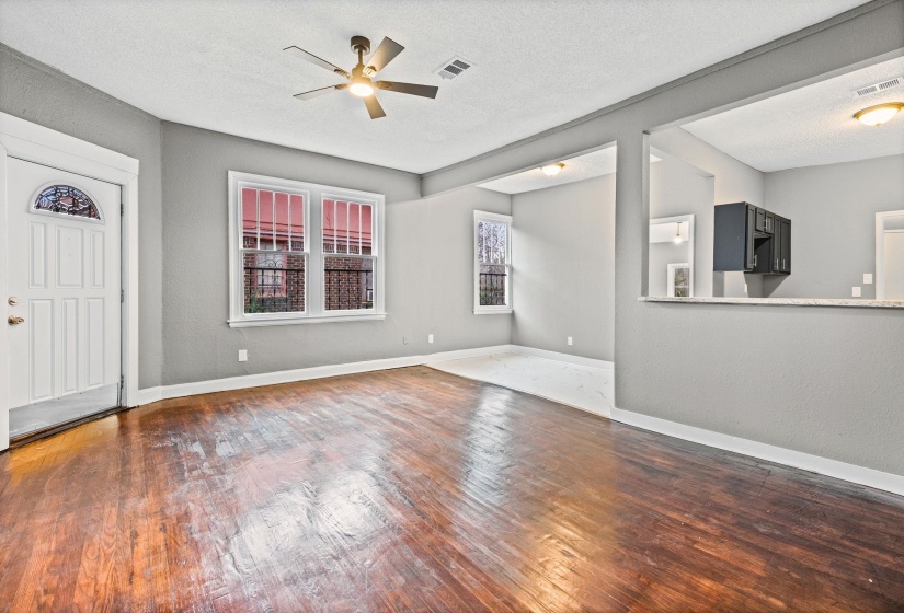 Unfurnished living room with a textured ceiling, dark wood-style flooring, and ceiling fan