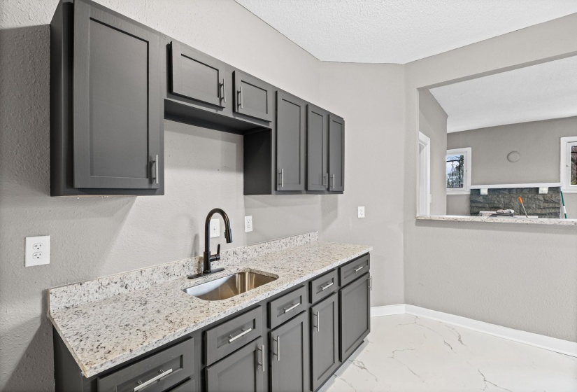 Kitchen featuring gray cabinetry, light marble finish flooring, light stone countertops, and a textured ceiling