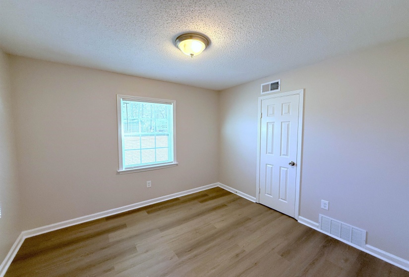 Empty room with a textured ceiling and wood finished floors