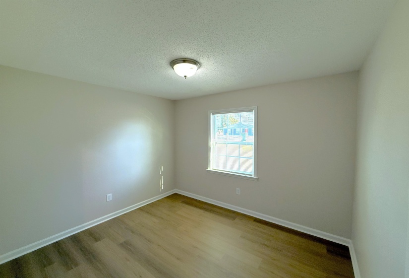 Unfurnished room with a textured ceiling and wood finished floors