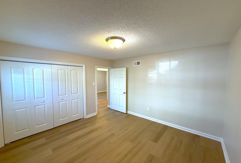 Unfurnished bedroom with a textured ceiling, wood finished floors, and a closet