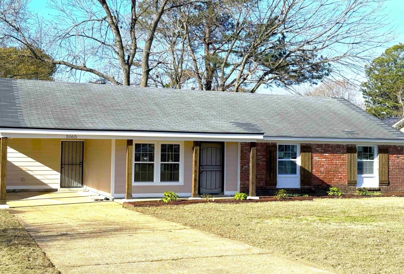 Ranch-style home featuring roof with shingles, a front yard, a porch, and brick siding