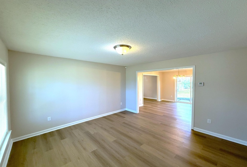 Empty room featuring a textured ceiling, wood finished floors, and a chandelier