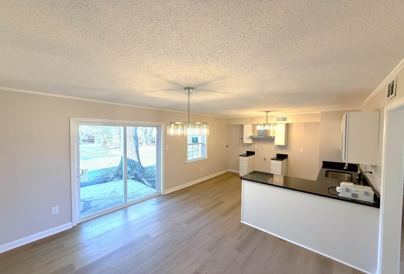 Kitchen featuring dark countertops, a peninsula, crown molding, a chandelier, and pendant lighting