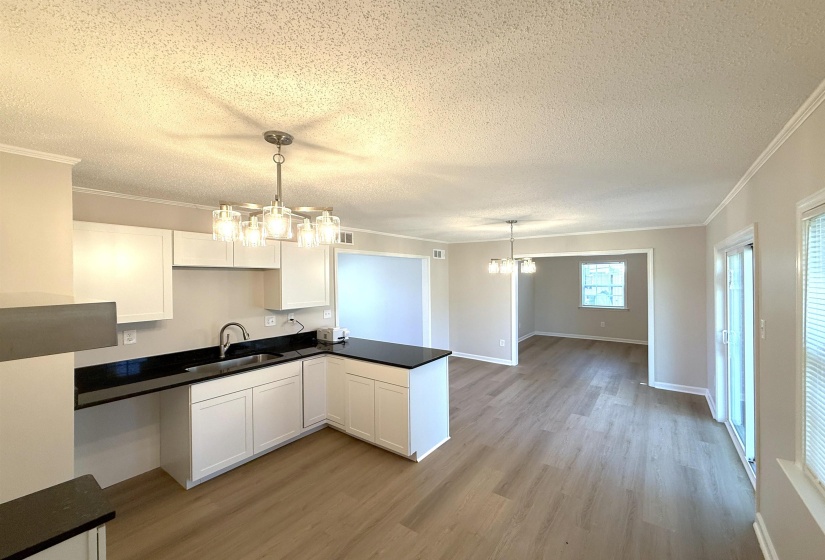 Kitchen with dark countertops, a chandelier, white cabinetry, a textured ceiling, and pendant lighting