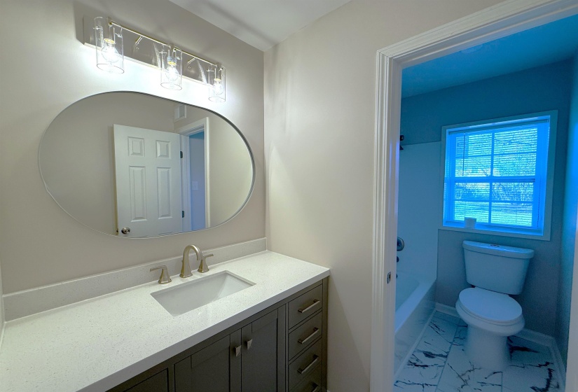 Bathroom with light marble finish floors, vanity, and tub / shower combination