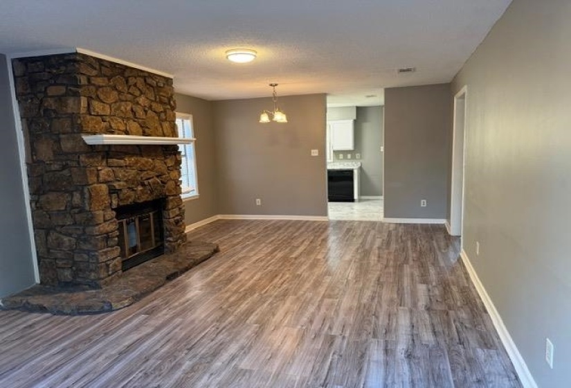 Unfurnished living room featuring a fireplace, a chandelier, dark wood-style floors, and a textured ceiling