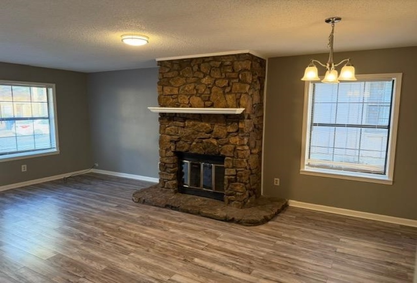 Unfurnished living room featuring a fireplace, a textured ceiling, plenty of natural light, and dark wood-style flooring